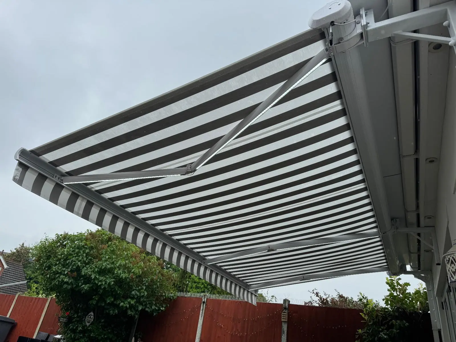 White and Grey Striped Residential Awning Installation - Stylish Sun Protection for Patio