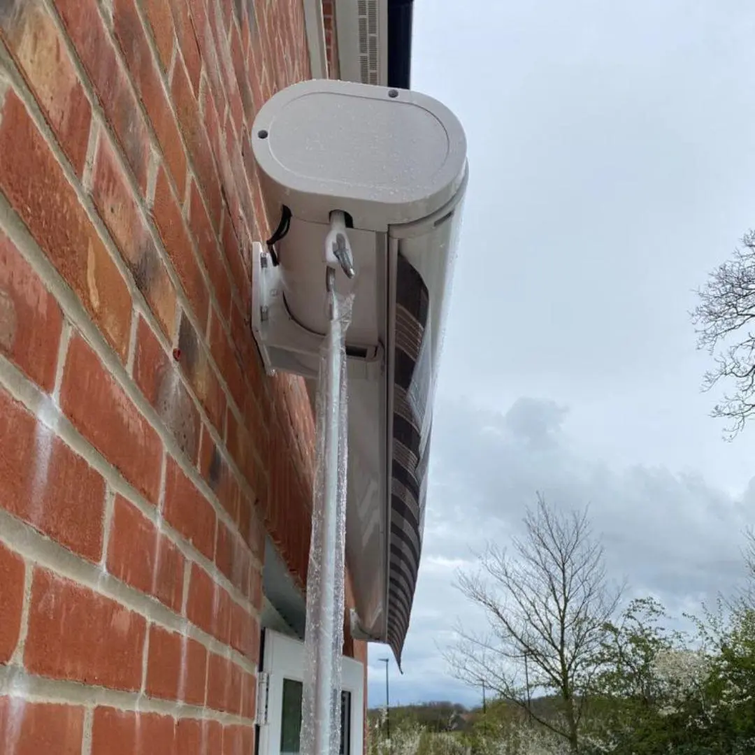 White retractable awning housing installed on a brick wall exterior.